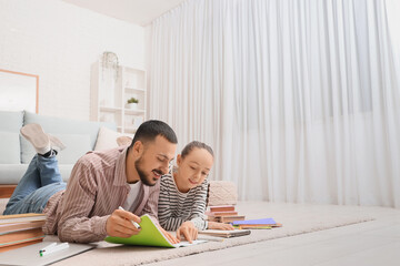 Teenage girl studying with tutor on floor at home