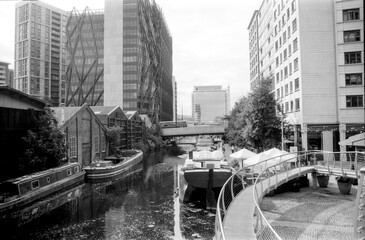 Canal boats docked in birmingham with modern buildings and bridges in background in monochrome analog style