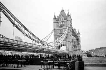 Obraz premium Tower bridge standing tall over outdoor cafe in london, uk, grainy black and white analog photo