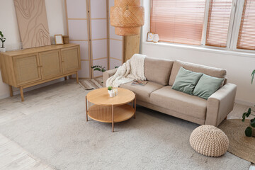 Interior of living room with sofa, table, chest of drawers and folding screen