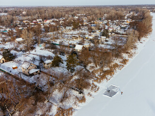 Aerial view of snow-covered houses near frozen river in Uralsk, Kazakhstan, during winter. c.