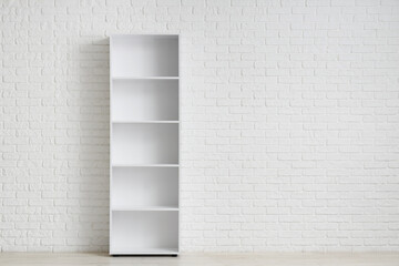Empty bookshelf near white brick wall in room