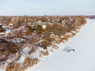 Aerial view of snow-covered houses near frozen river in Uralsk, Kazakhstan, during winter. c.