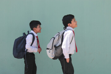 Two dark-skinned Latino boys carry their backpacks and walk back to school to study and learn