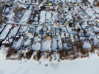 Aerial view of snow-covered houses near frozen river in Uralsk, Kazakhstan, during winter. c.