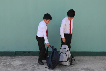 Two dark-skinned Latino boys carry their backpacks and walk back to school to study and learn
