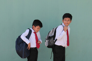 Two dark-skinned Latino boys carry their backpacks and walk back to school to study and learn