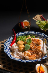 Food concept Thai authentic kanom jeen Nam Ya fermented rice noodles served with a fish flavorful curries fresh and vegetables on black background with copy space