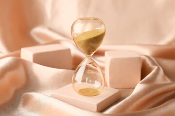 Crystal hourglass and podiums on beige background