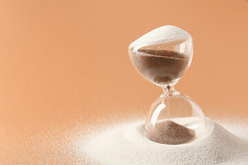 Crystal hourglass and sand on beige background
