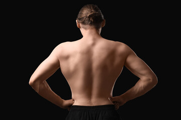 Sporty muscular man on black background, back view