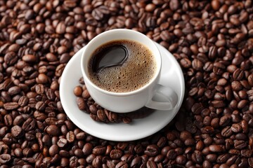 Fototapeta premium Coffee cup on saucer surrounded by coffee beans