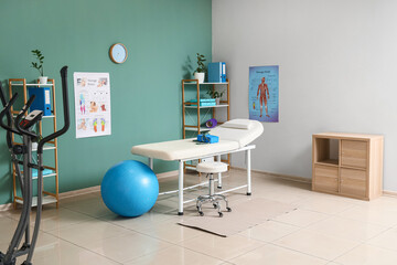 Interior of physiotherapist's office with couch, shelf units and fitball