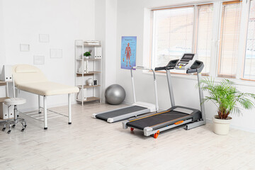 Interior of physiotherapist's office with couch, treadmills and shelf unit