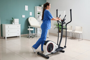 Female physiotherapist with exercising bike in office