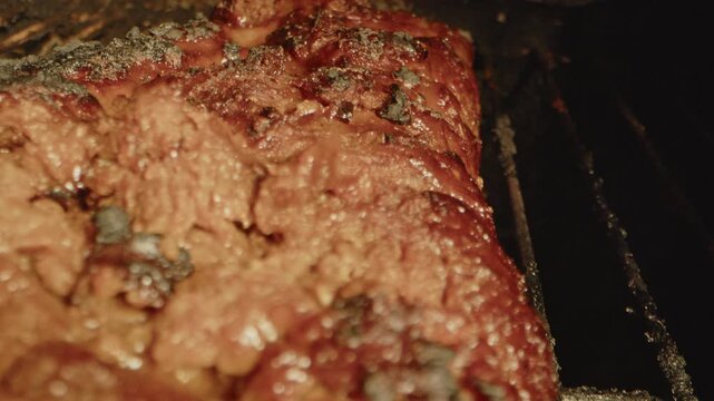 Macro dolly out of a delicious slab of spareribs on a barbecue with scorched peaces of meat