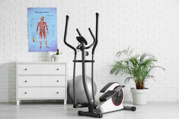 Interior of physiotherapist's office with poster and exercising bike