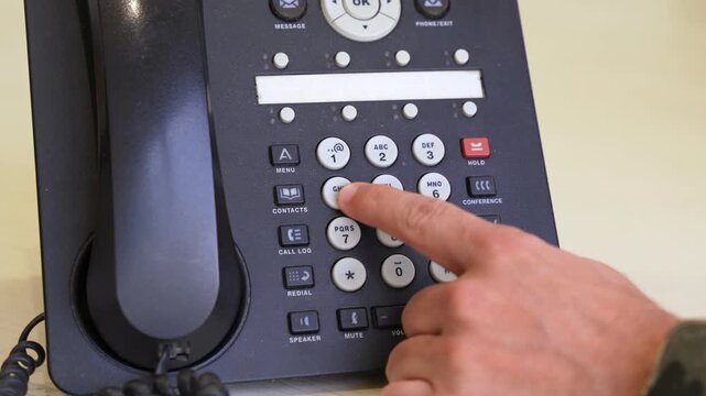 Finger pressing buttons on a landline office phone. Perfect for business, communication, tech tutorials, or customer service visuals.