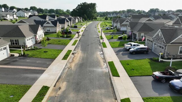 Proud and patriotic American neighborhood with luxury single family houses in brick design. Sunset time in American suburbia at sunset. Aerial forward dolly shot. Quiet and peaceful community life.