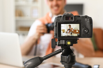 Naklejka premium Male blogger with photo camera recording video on screen at home, closeup