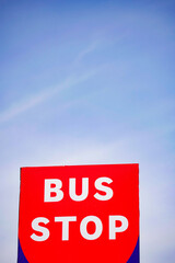 Brightly colored bus stop sign against a clear sky