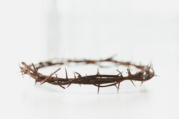 Crown of thorns on white table background. Easter, central celebration in Christianity, honors...