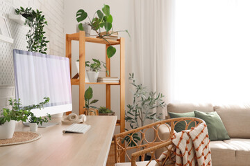 Interior of modern office with workplace, shelf unit and green plants