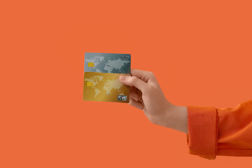 Female hand with credit cards on orange background
