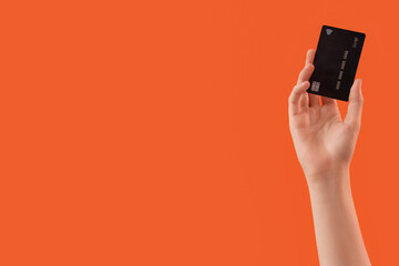 Female hand with credit card on orange background