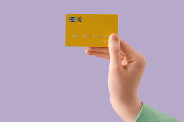 Female hand with credit card on lilac background, closeup