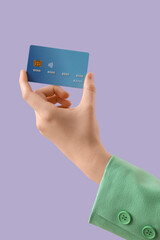 Female hand with credit card on lilac background