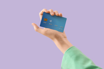 Female hand with credit card on lilac background