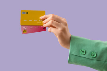 Female hand with credit cards on lilac background