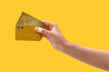 Female hand with credit cards on yellow background