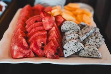 Cut of watermelon, cut dragon fruit served on white tray at the buffet