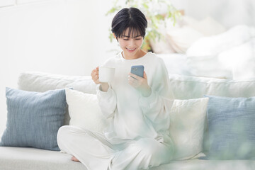 パジャマでスマートフォンを操作する女性