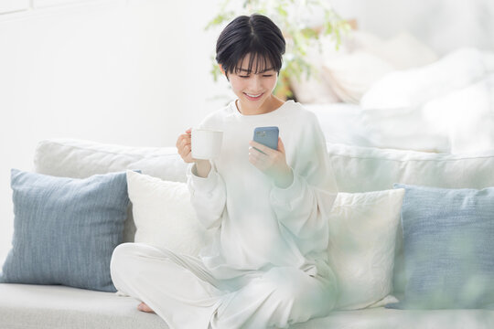 パジャマでスマートフォンを操作する女性