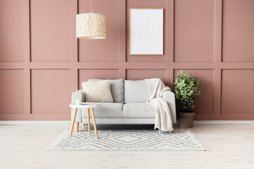 Comfortable sofa, table and houseplant near brown wall in interior of living room