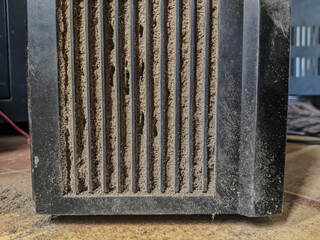 Close-up of a heavily dust-laden black electronic device vent, showing thick layers of dirt...