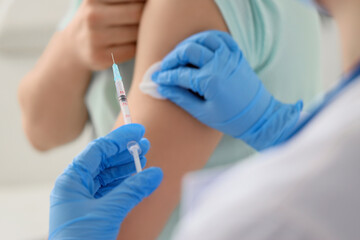 Doctor disinfecting man's arm before vaccination man in clinic, closeup