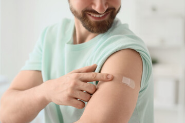 Young man with applied medical patch after vaccination in clinic, closeup
