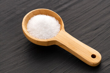 Fine crystals of refined white sugar on a wooden spoon - Saccharum officinarum