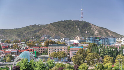 Aerial timelapse of Rike Park, a modern urban park in Tbilisi's Old Town with green trees and lawns. The Bridge of Peace in the background. Georgia © HyperlapsePro