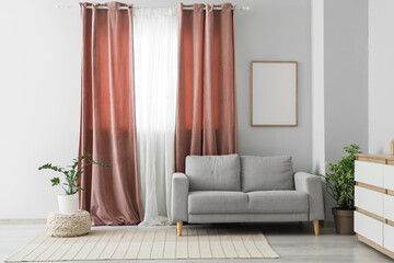 Interior of living room with pink curtains, sofa and plants