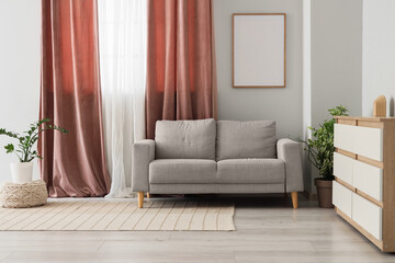 Interior of living room with pink curtains, sofa and plants