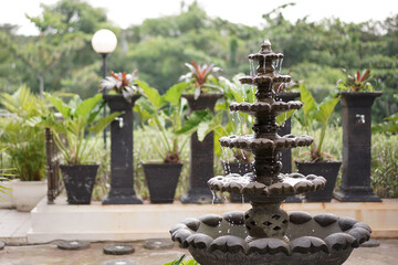 A classic tiered stone water fountain creating a tranquil and relaxing atmosphere in a lush green...
