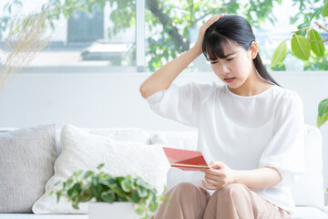 リビングで通帳を見る若い女性