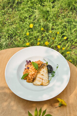 Halibut steak with tomato bulgur in bright outdoor setting, overhead composition