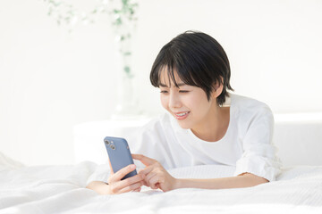 うつ伏せでスマホを操作する女性