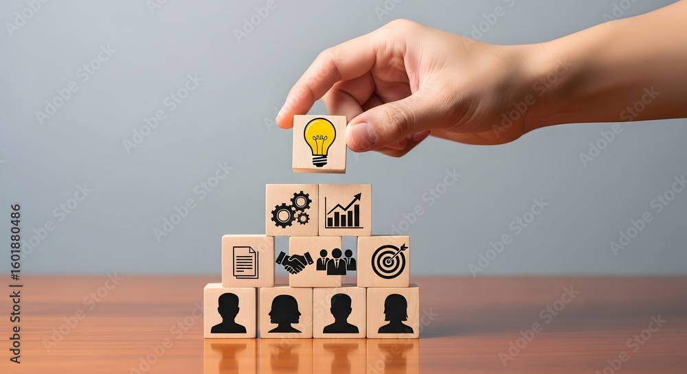 Aufkleber hand placing a lightbulb block on top of a pyramid of wooden blocks with business icons on them